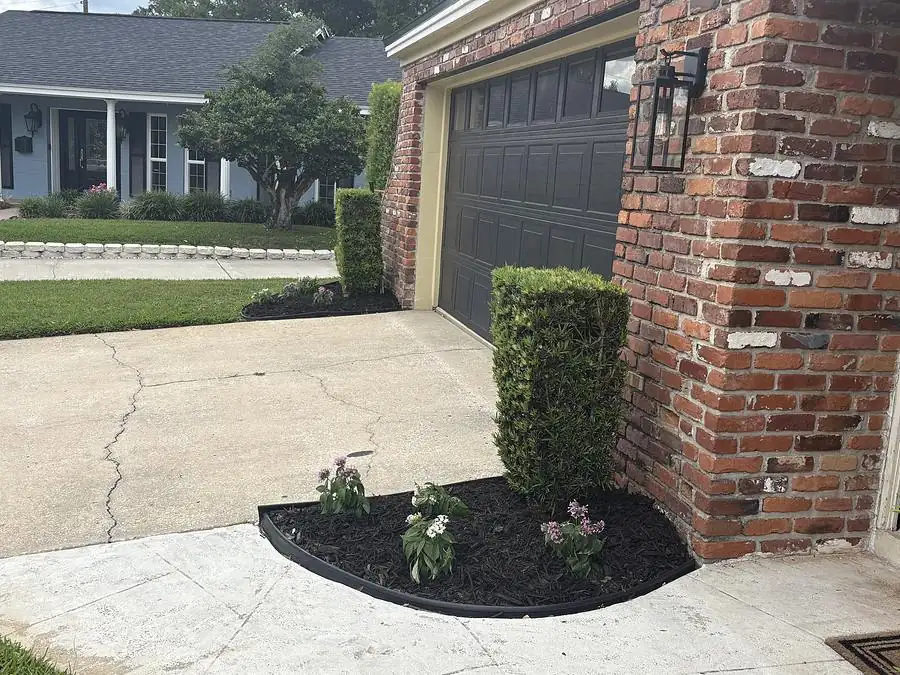Brick home driveway with trimmed shrubs and a new mulch bed at the garage